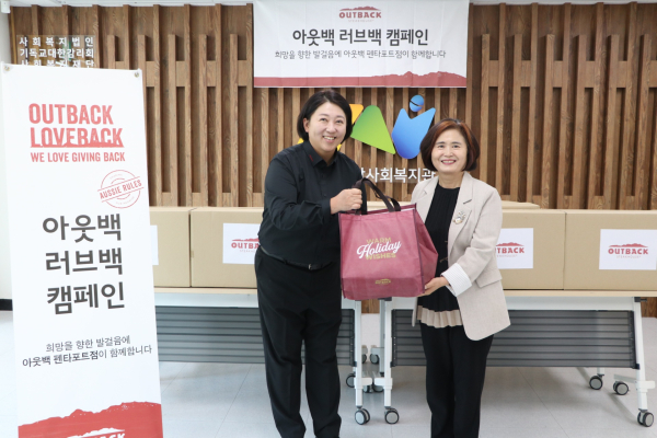 아웃백 천안펜타포트점 박금석 점주(왼쪽)가 천안시장애인종합복지관 문명희 관장에게 도시락 세트를 제공하고 있다./사진=다이닝브랜즈그룹
