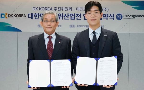 마인즈그라운드(주) 민환기 대표(사진 오른쪽)와 DX KOREA 2026 김영후 추진위원장이 12일 대한민국 방위산업전(DX KOREA) 2026 업무협약서를 체결하고 기념촬영하고 있다 / 사진= 마인즈그라운드.
